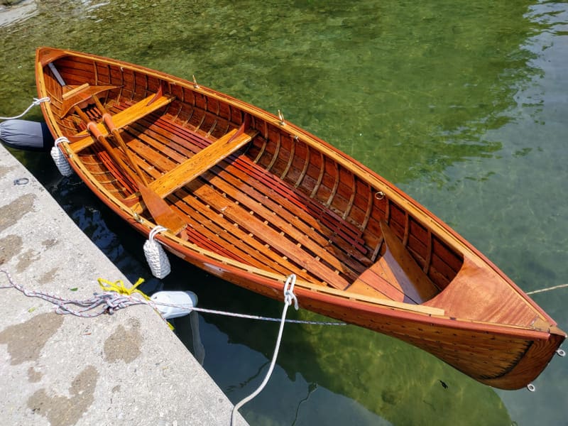 Empty wooden boat tied to pier