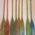 Seven artistic wooden paddles displayed vertically