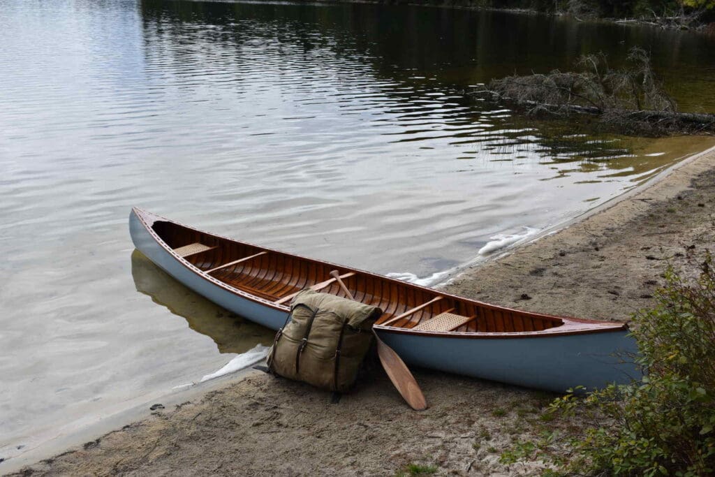 Canoe on sandy lakeshore with backpack