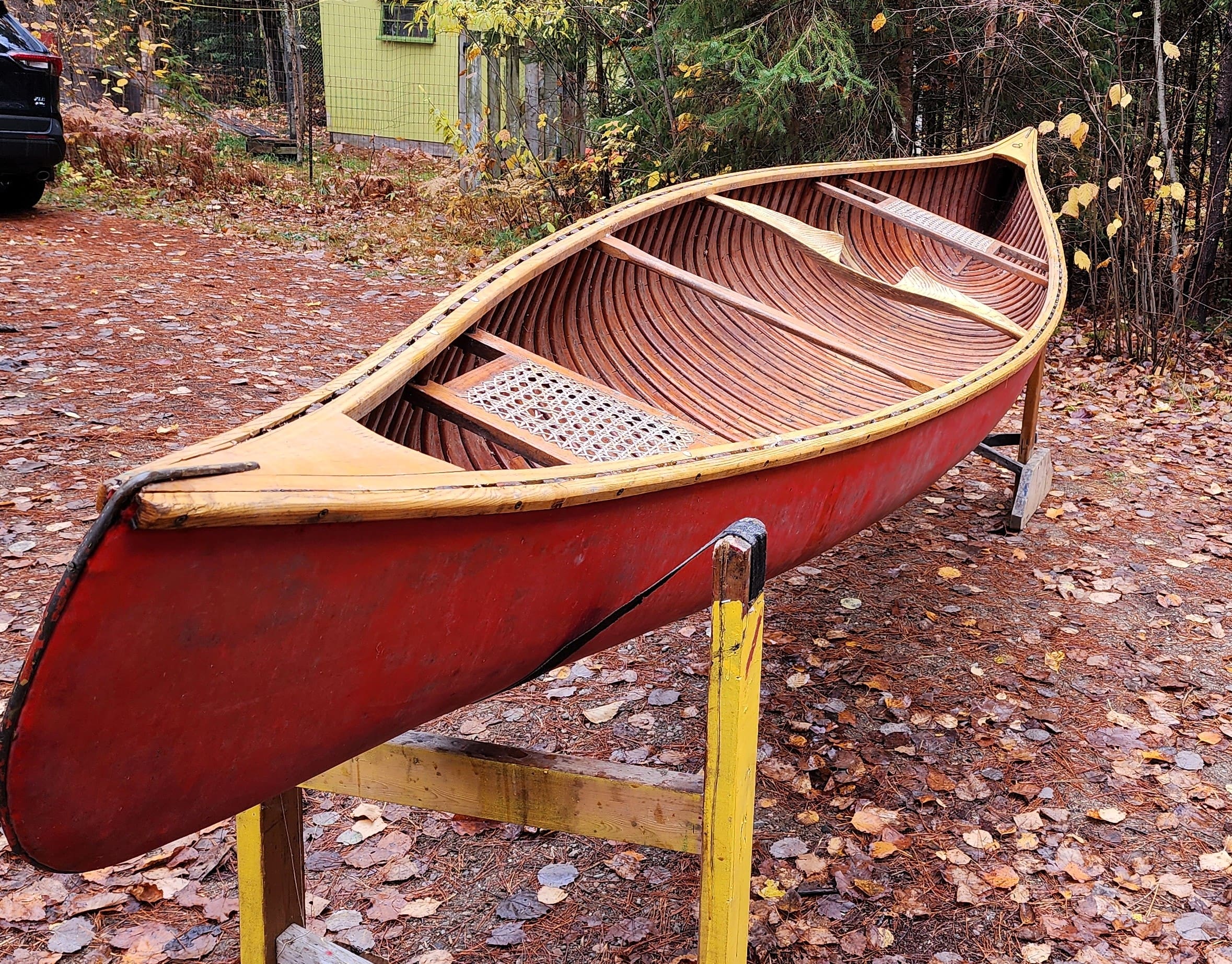 Red canoe resting on wooden stands outdoors.