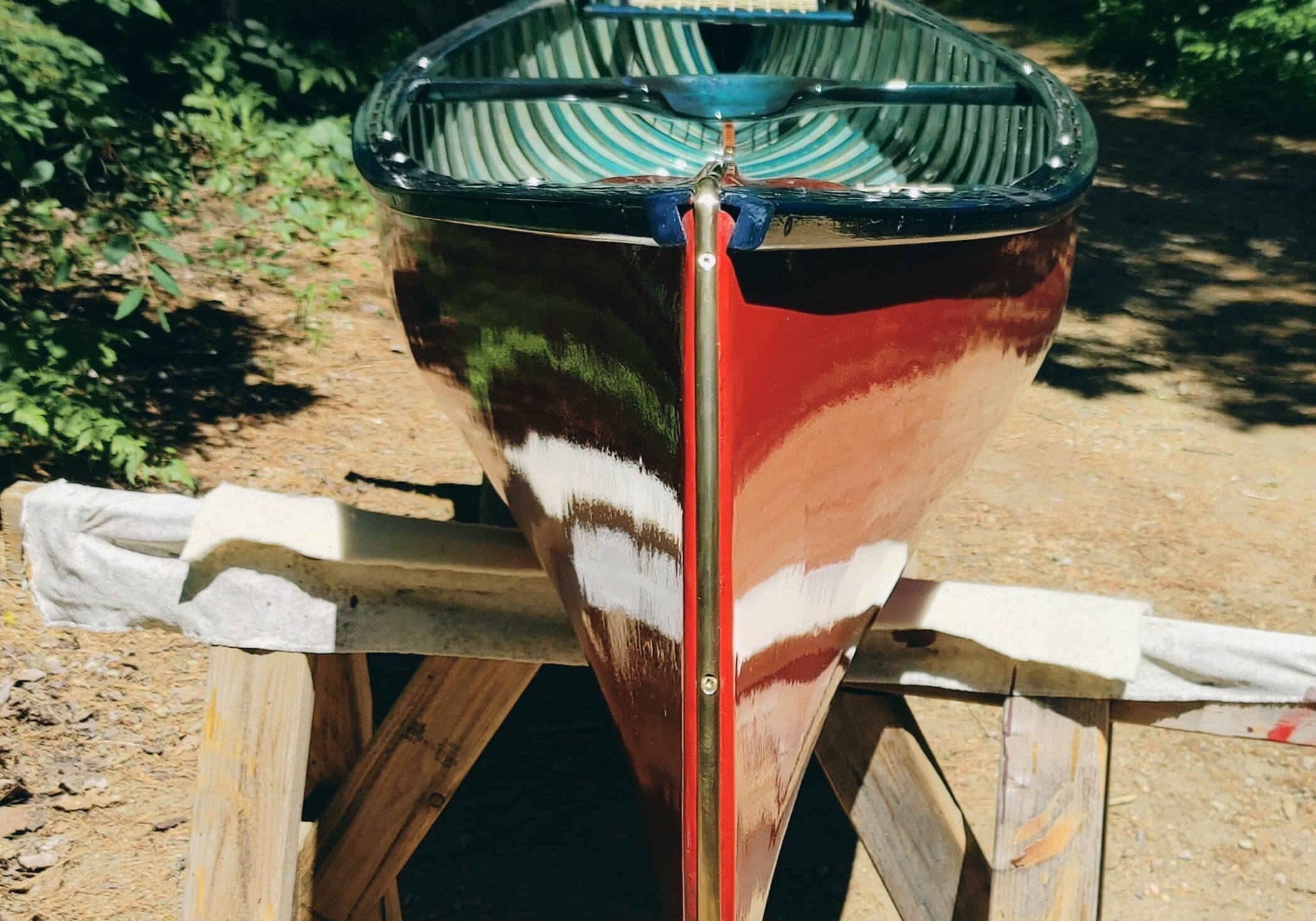 Red and green kayak resting on a wooden rack outdoors.